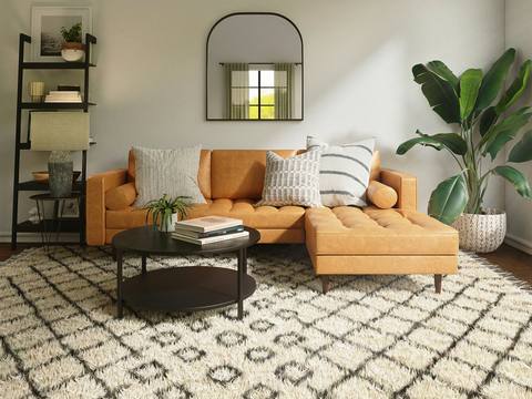 A living room with an orange sofa and patterned rug