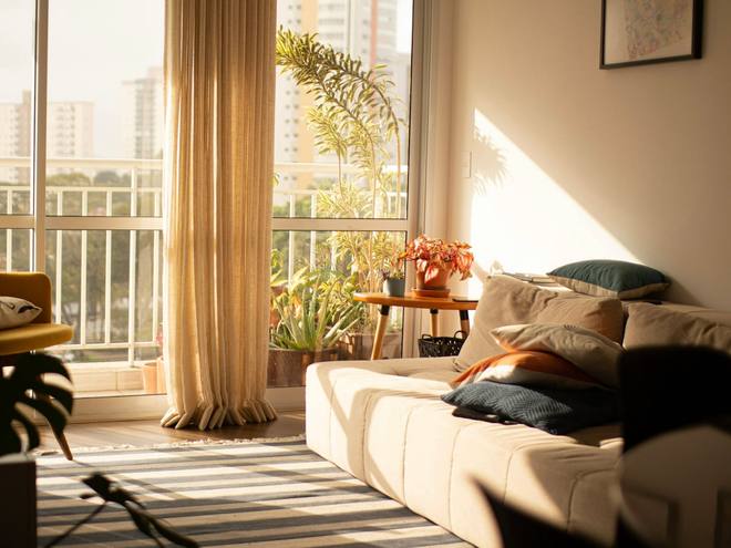 A sunny living room with a balcony and floor-length curtains