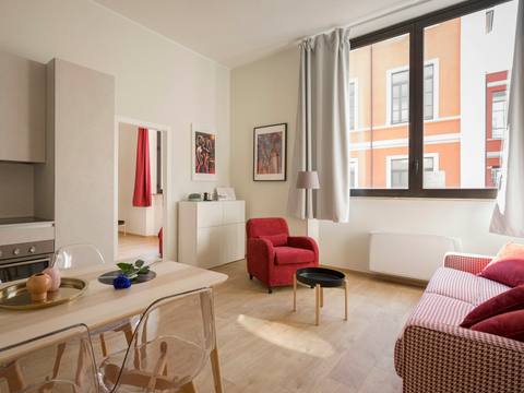 An open-plan room with a red armchair and a dining table