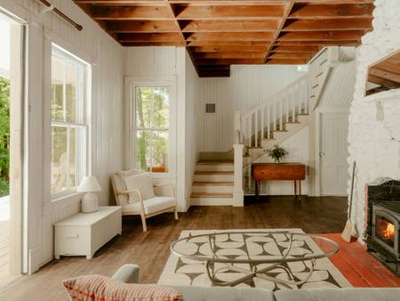 A bright living room with beams, a staircase and a wood burner
