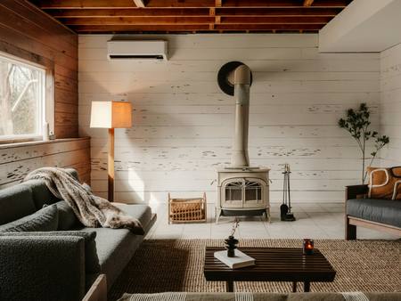 A sitting room with a wood burner, sofa and lamps