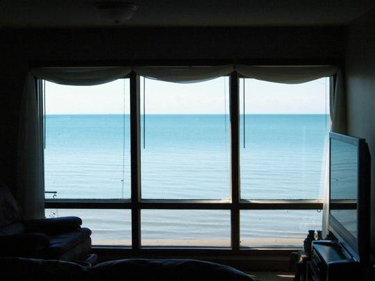 A living room with a wall of windows looking out to sea