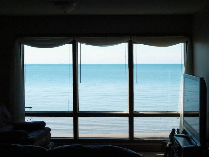 A living room with a wall of windows looking out to sea