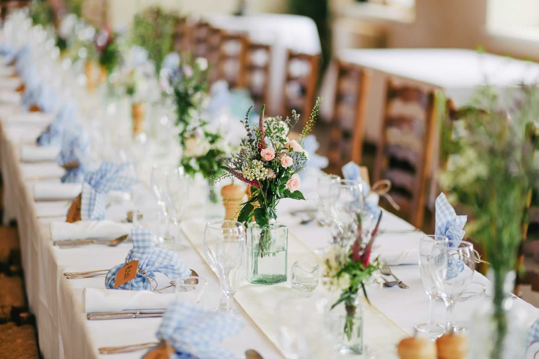 A long table laid with flowers and blue napkins for a garden reception
