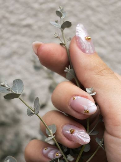Nude nails with tiny gem details holding a eucalyptus sprig