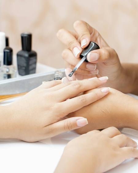 A nail technician painting a client’s nails