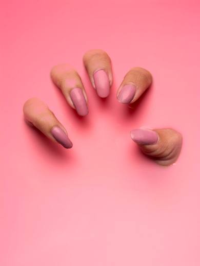 Almond nails in a soft nude on a pink background