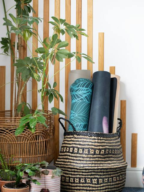 Rolled yoga mats in a woven basket with plants