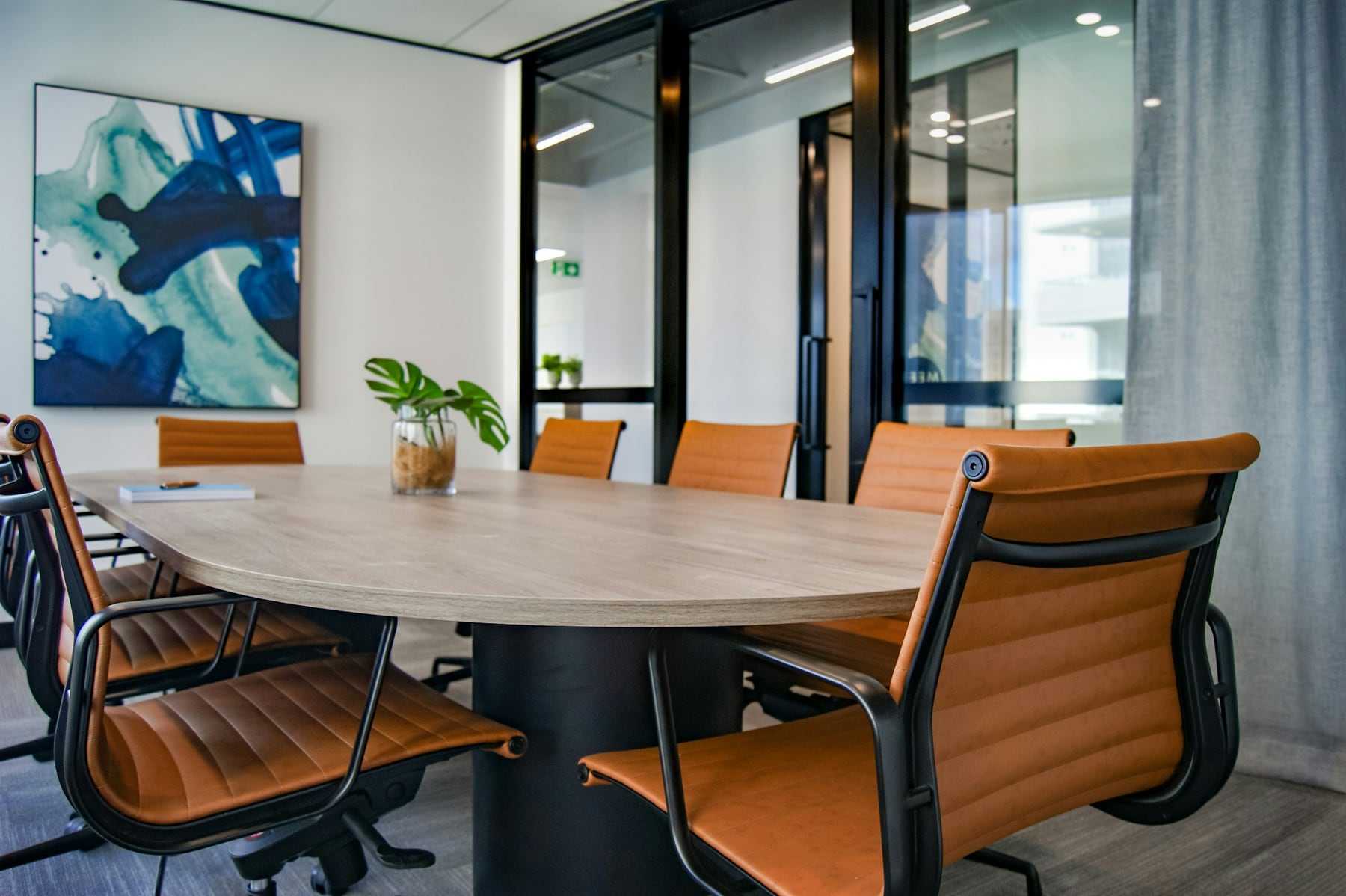 A meeting room with a round table and orange chairs