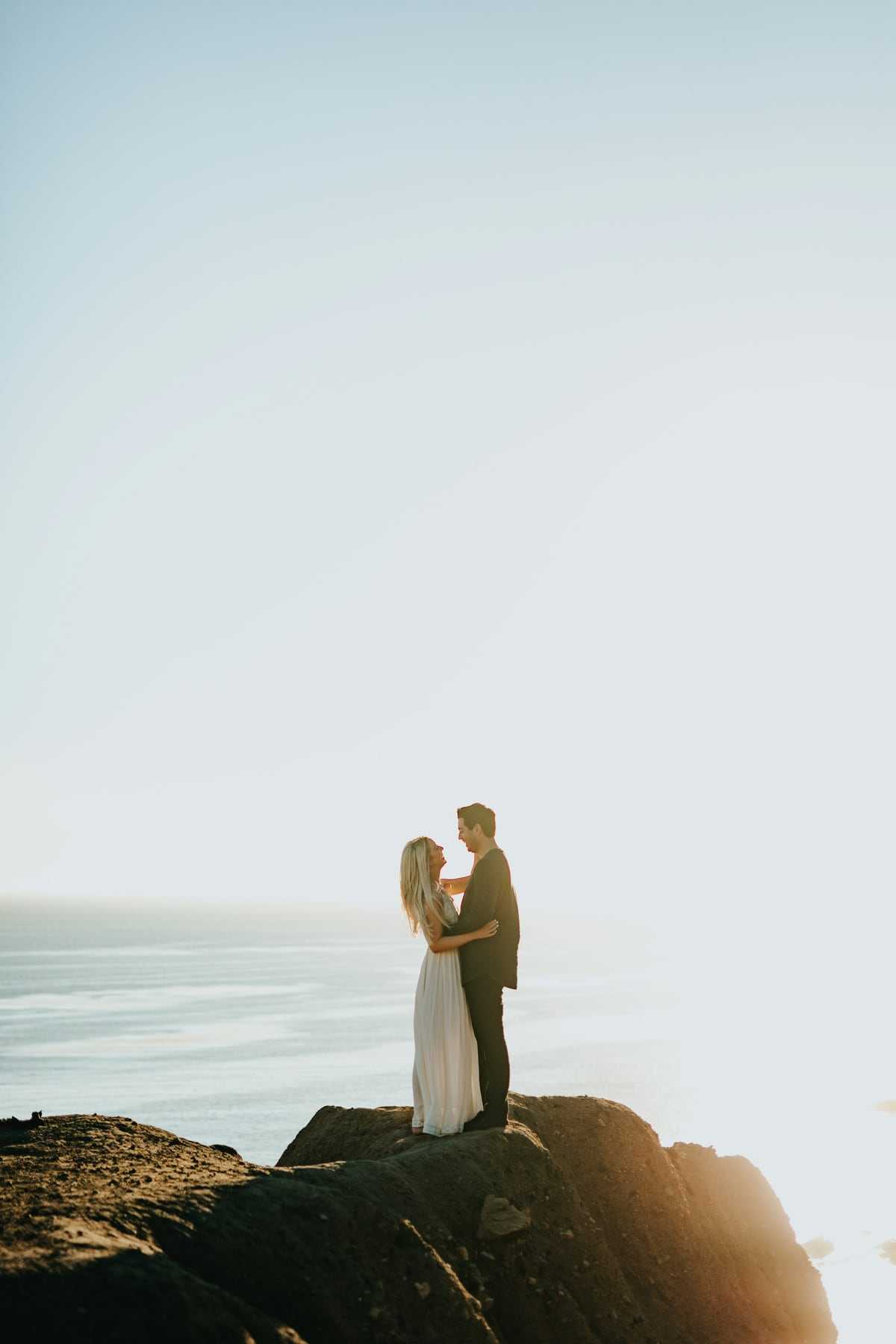 A couple standing on a clifftop above the sea in soft mist