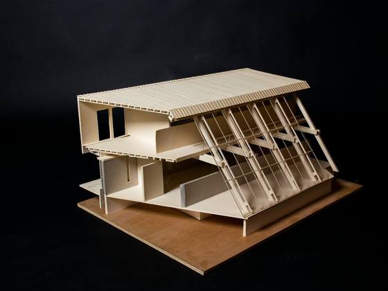 A timber architectural model of a house on a dark table