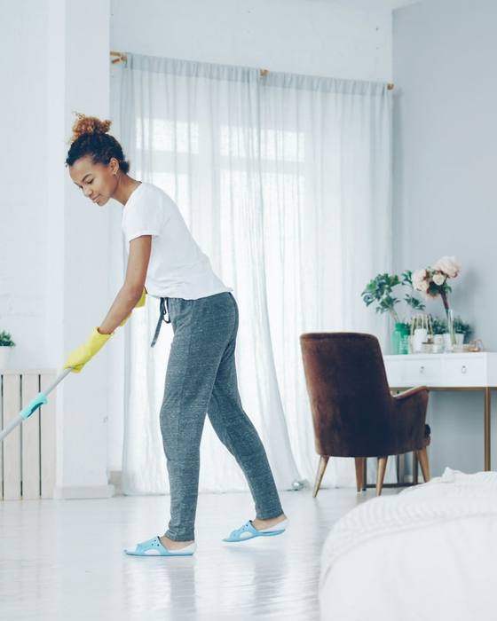 A cleaner mopping a bright living room floor