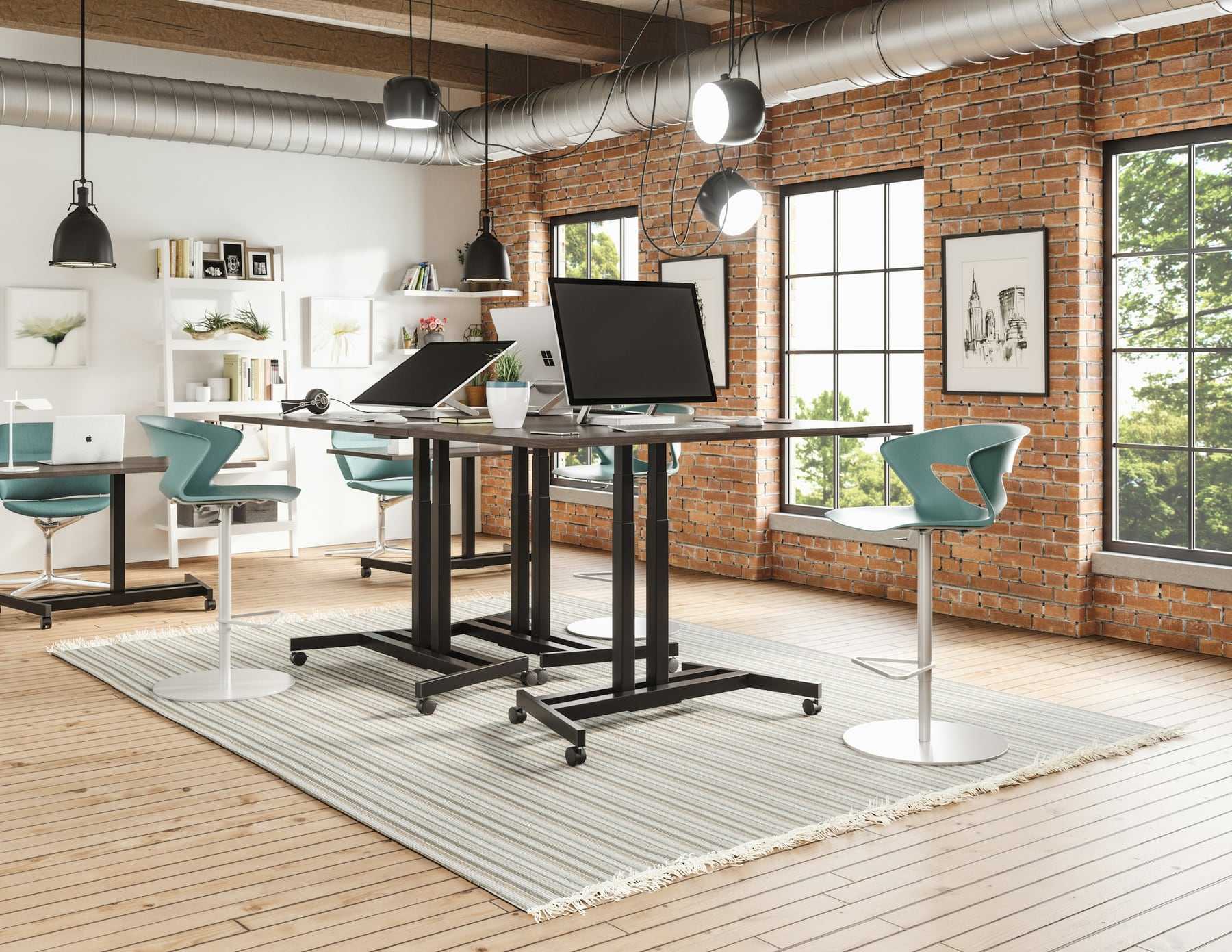 A bright open-plan office with brick walls and standing desks