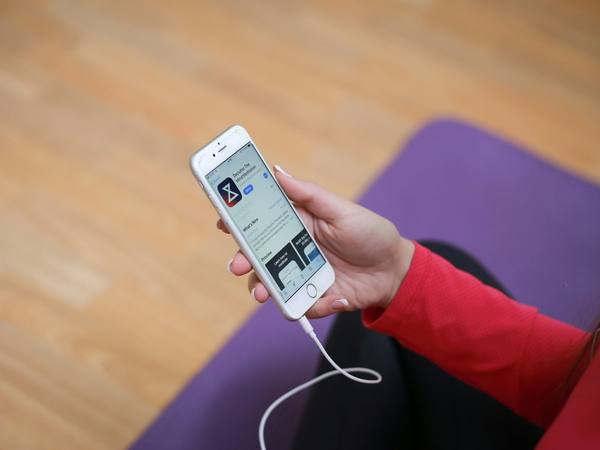 A phone showing a workout video on a yoga mat