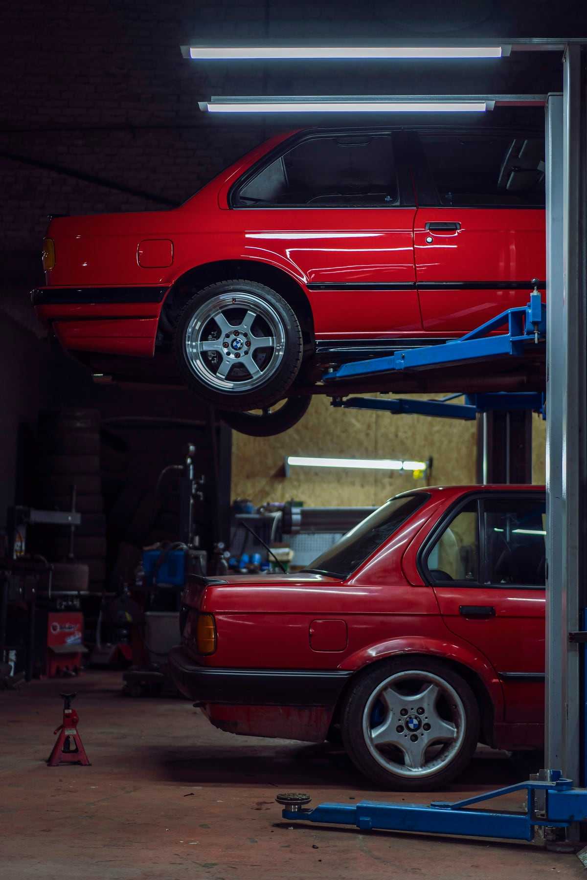 A red classic car raised on a two-post lift