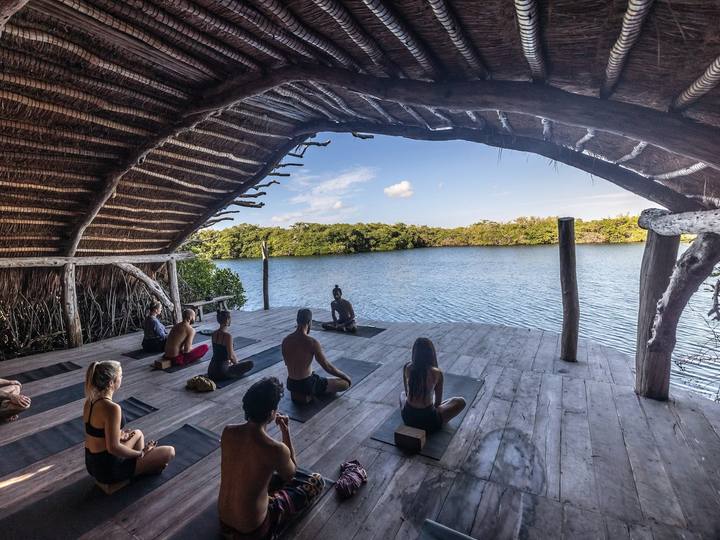 A yoga class on a wooden deck looking out over a lake