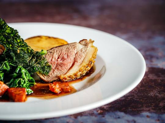 Slices of pink roast lamb with greens and gravy