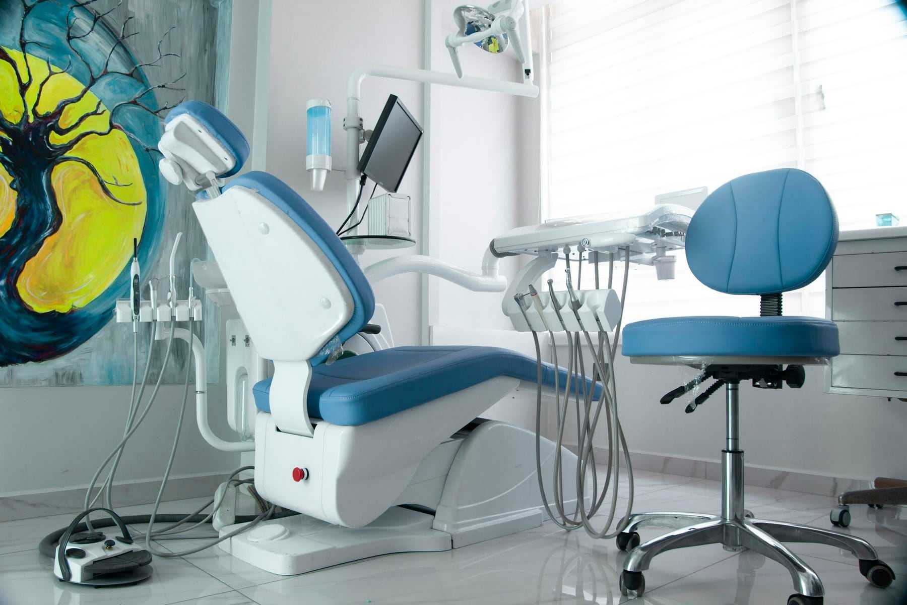 A bright treatment room with a blue dental chair