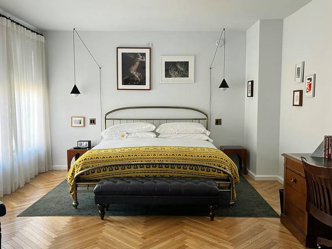 A bright bedroom with a black iron bed and framed prints