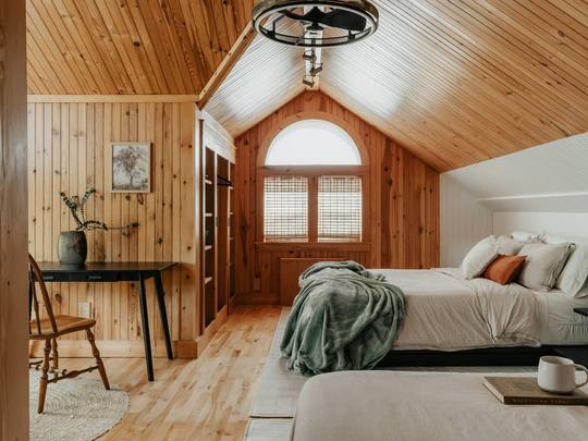 A wood-panelled bedroom with an arched window