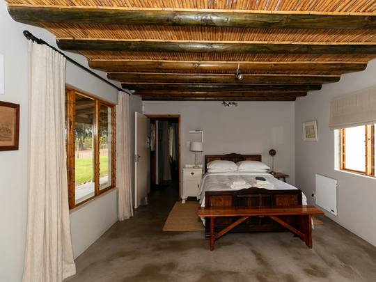 A bedroom with a dark beamed ceiling and a bench at the foot of the bed