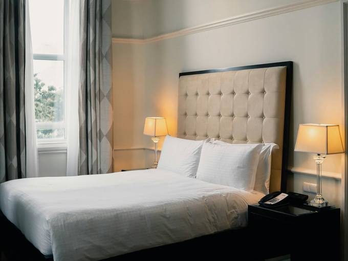A neat double bed with a tall upholstered headboard