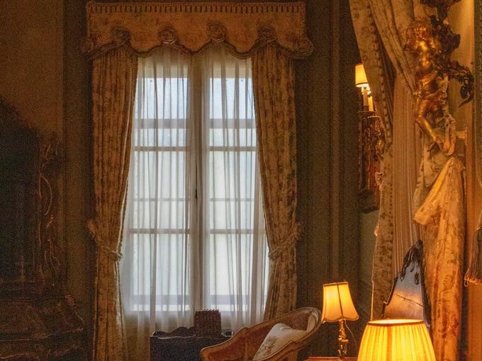 A heritage bedroom with heavy curtains and warm lamps