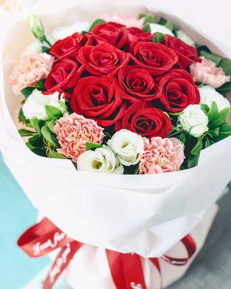 Red roses wrapped in white paper with a ribbon