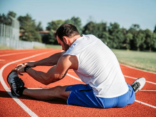 A runner stretching on an athletics track