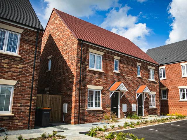 A row of new red brick houses with gable roofs on a sunny day