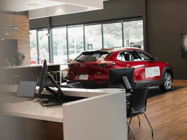 A bright showroom with a red car beside the sales desk