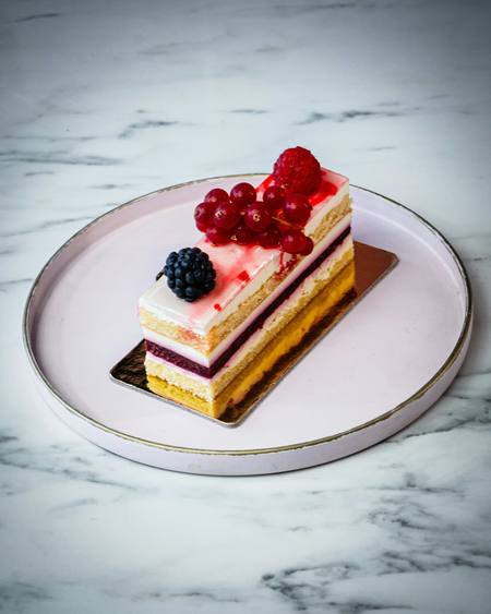 A slice of layered sponge topped with fresh berries