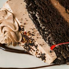 A slice of chocolate cake with cream and a cherry