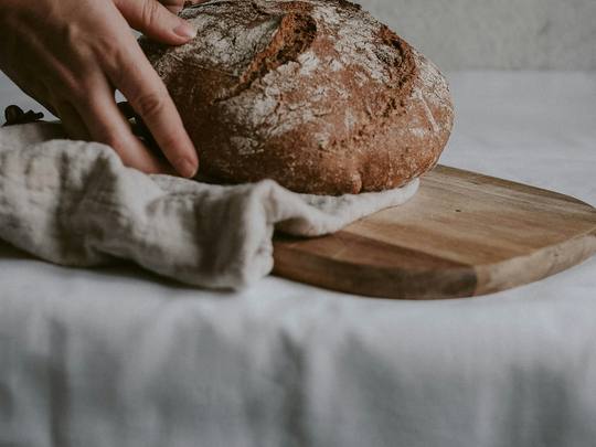 Hands shaping a sourdough loaf on a floured board