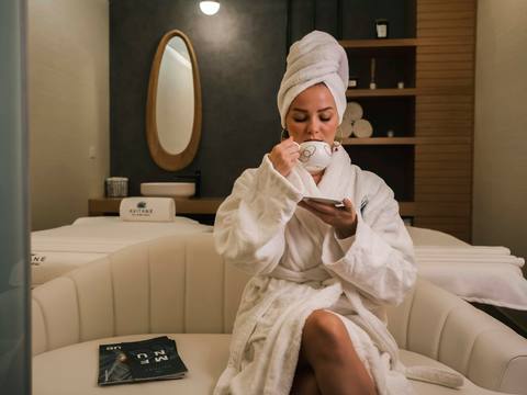 A guest relaxing in a white robe with a cup of tea