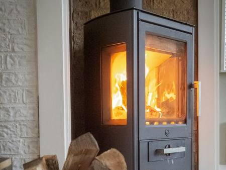 A wood stove beside a basket of logs
