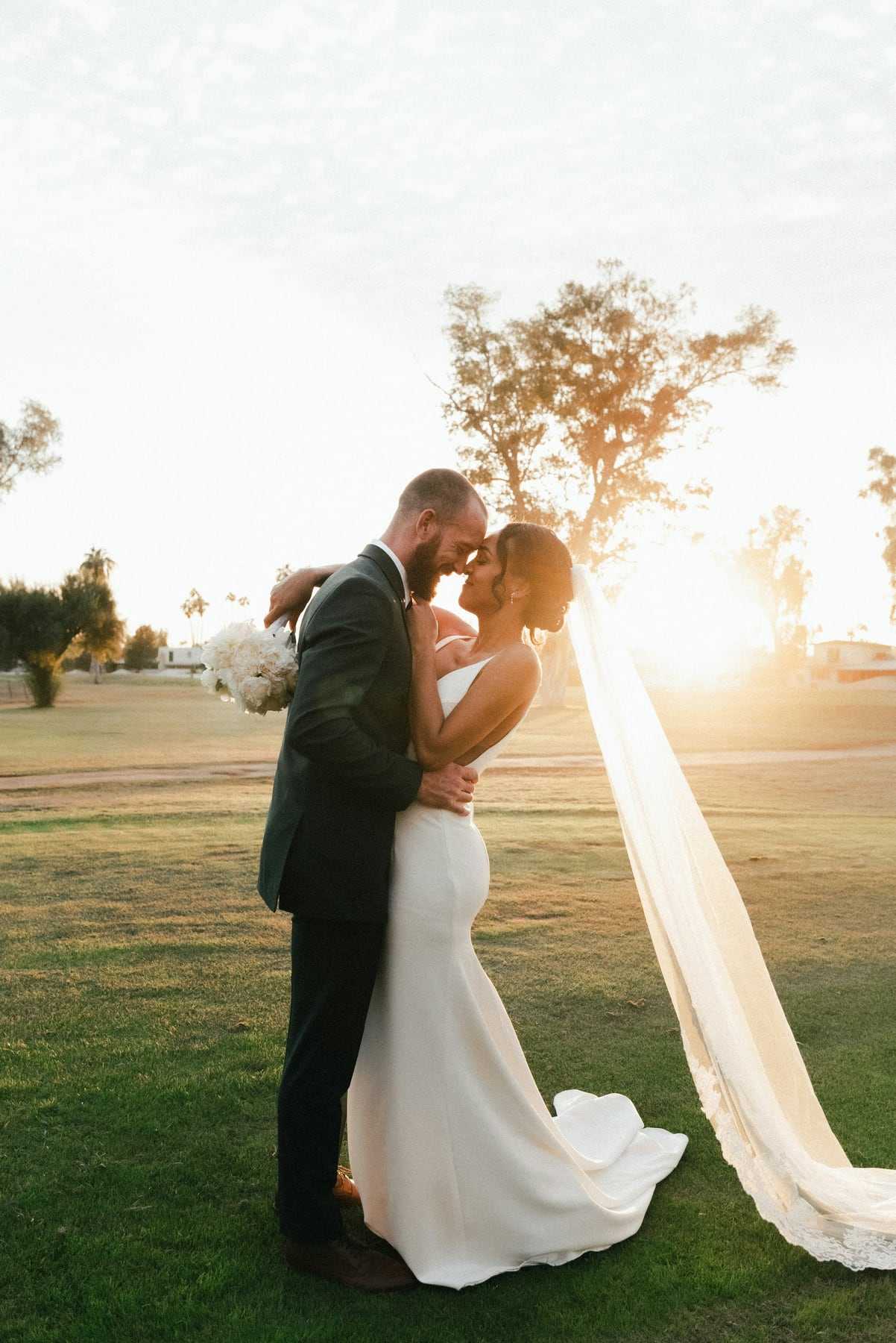A couple kissing at sunset with the veil blowing behind them
