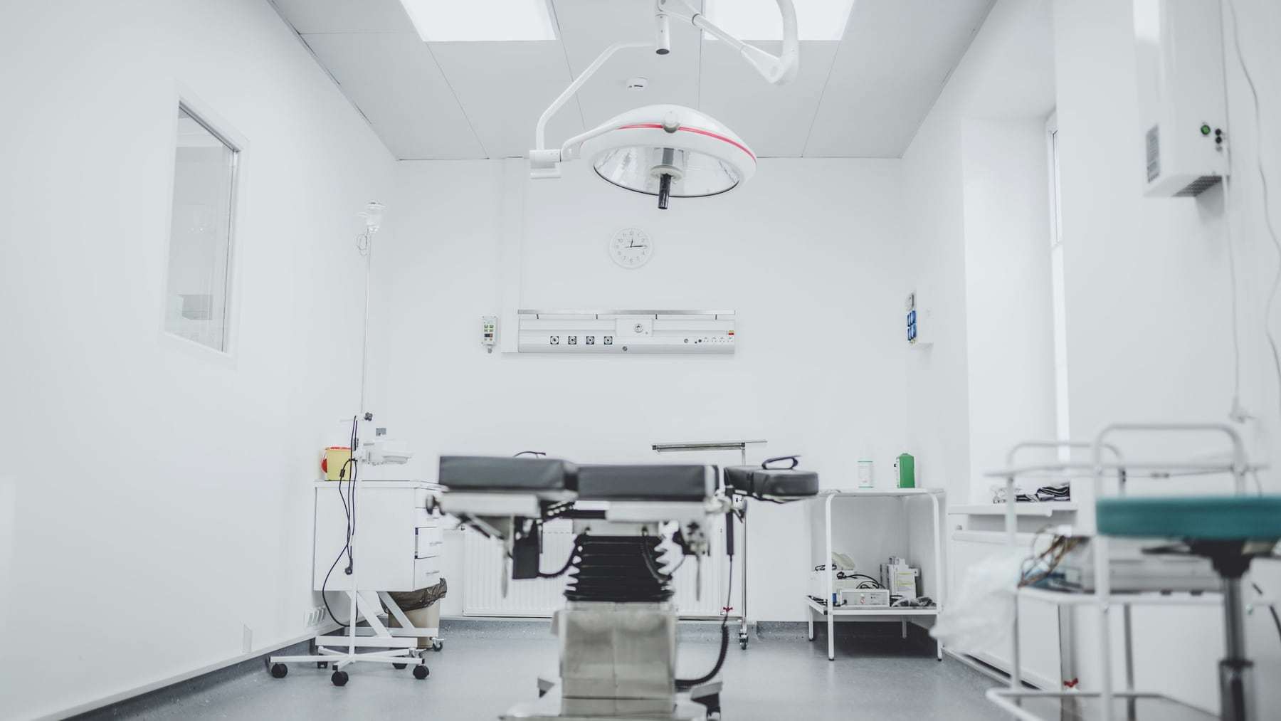 A clean, bright operating room with a surgical table and lights
