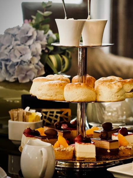 A three tier afternoon tea stand with scones and cakes