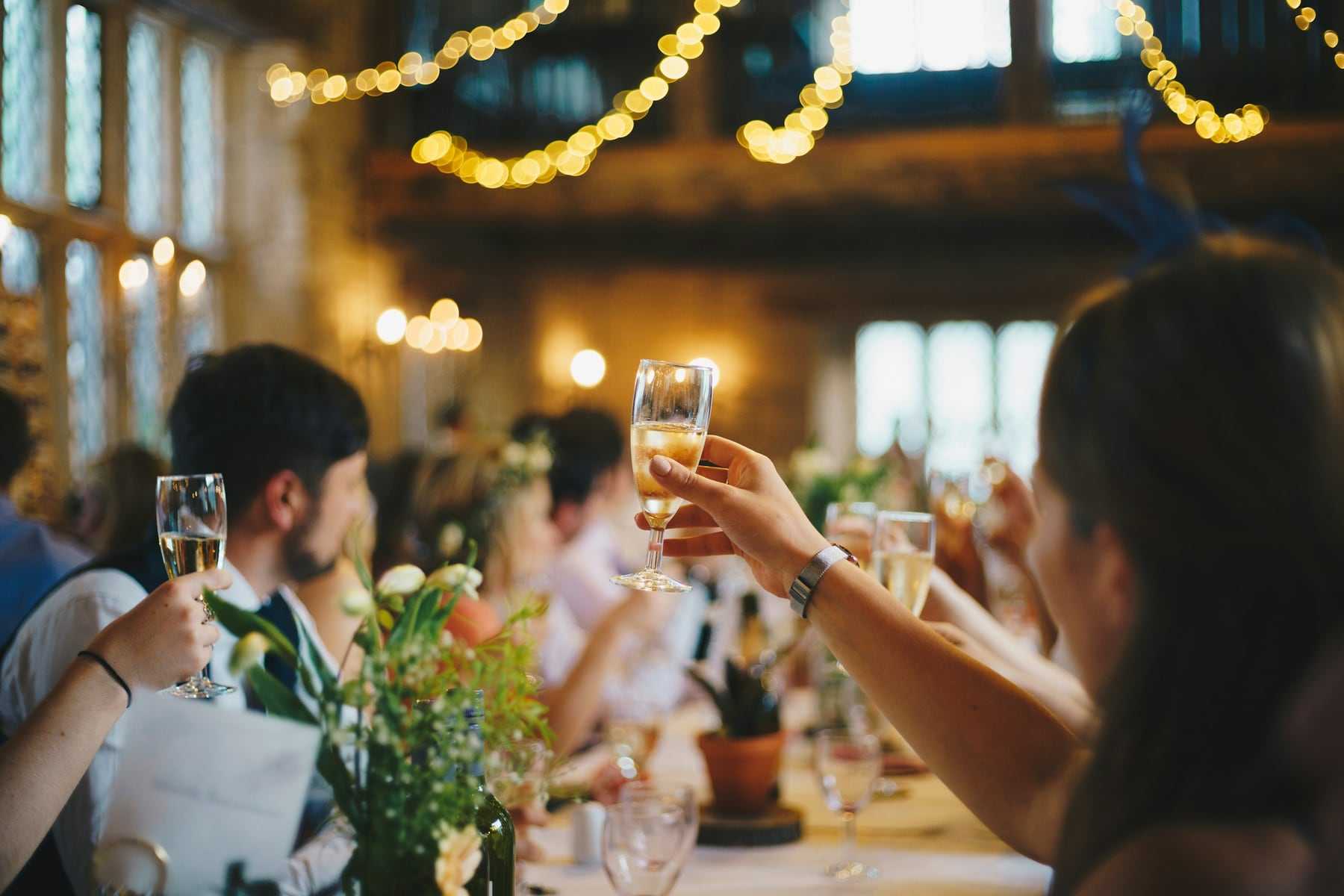 Guests raising glasses under strings of warm lights