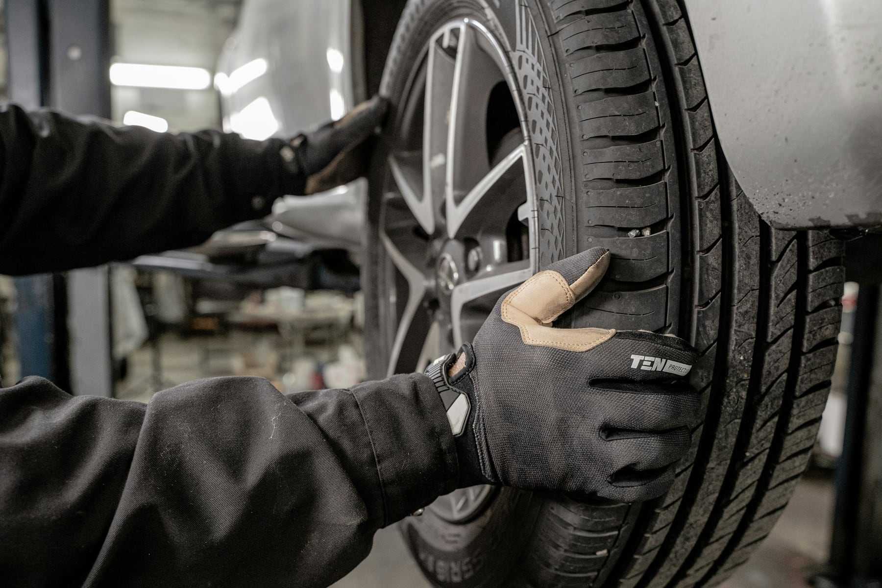 Gloved hands fitting a tyre to an alloy wheel