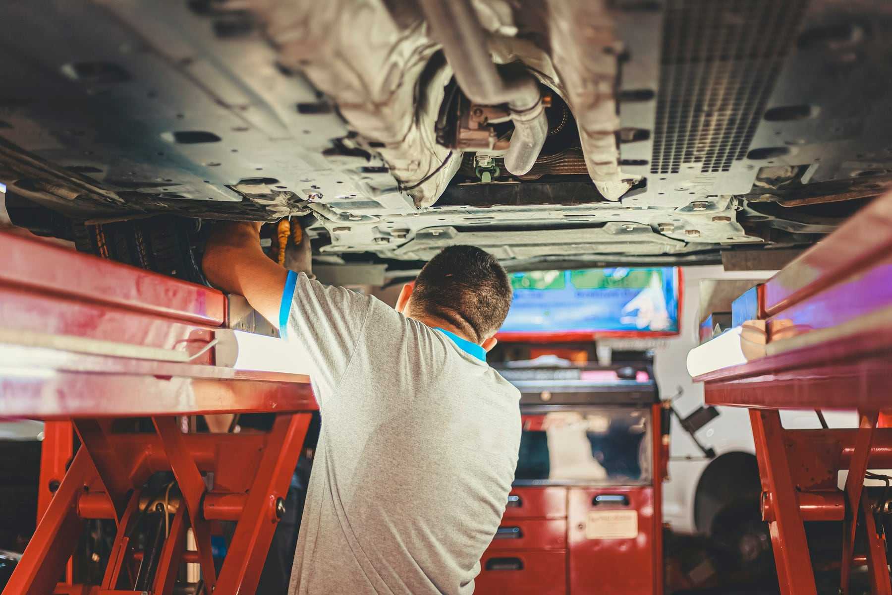 A technician working under a car raised on a lift
