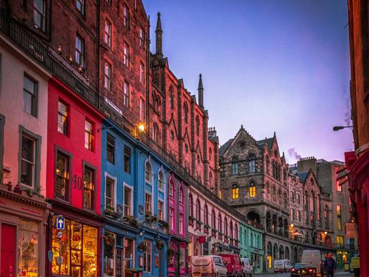 Coloured shopfronts curving down Victoria Street at dusk
