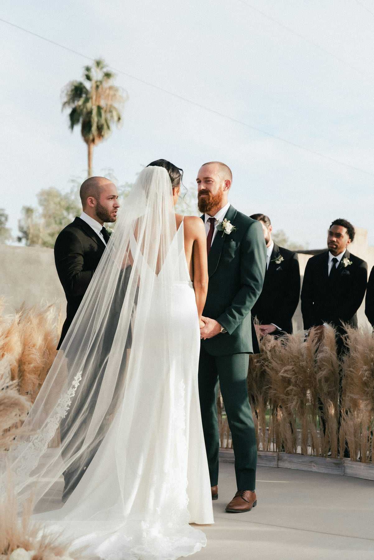 A bride and groom facing each other during the vows outdoors
