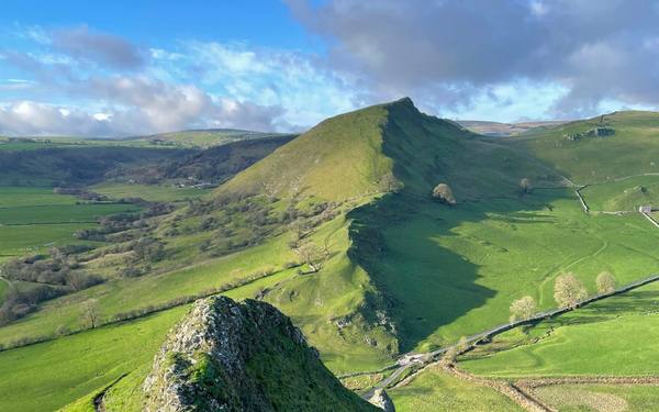 A grassy ridge running to a pointed peak under a blue sky