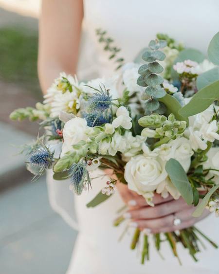A bride holding a white and green bouquet
