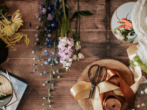 Scissors, ribbon and loose stems on the wooden workbench