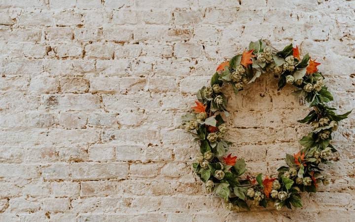 A finished flower wreath hanging on a white brick wall